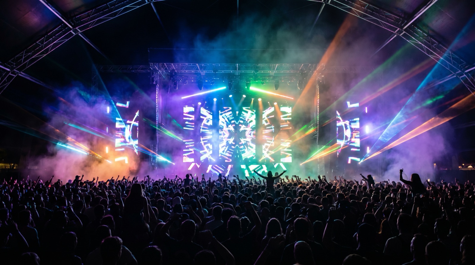 Wide photographic view of an outdoor electronic music festival main stage at night, dramatic stage lighting and a large crowd silhouette, no logos, no text, no signage, no recognizable people